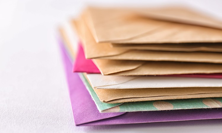 Stack of direct mail marketing envelopes in a variety of colors.