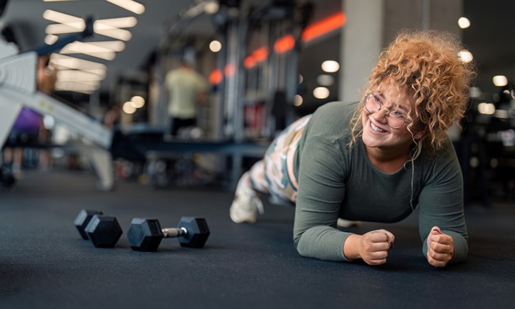 Young adult woman doing a plank at a gym.