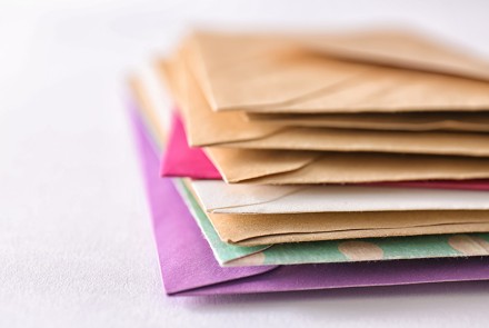 Stack of direct mail marketing envelopes in a variety of colors.