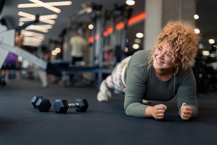 Young adult woman doing a plank at a gym.