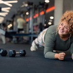 Young adult woman doing a plank at a gym.